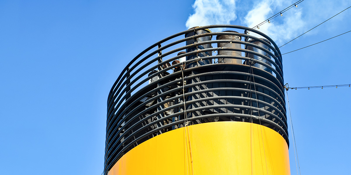 A yellow funnel of a ship emitting exhaust from its pipes.